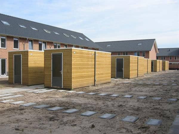 Berging met platdak en houtkleur op een parkeerplaats bij rijtjeshuizen