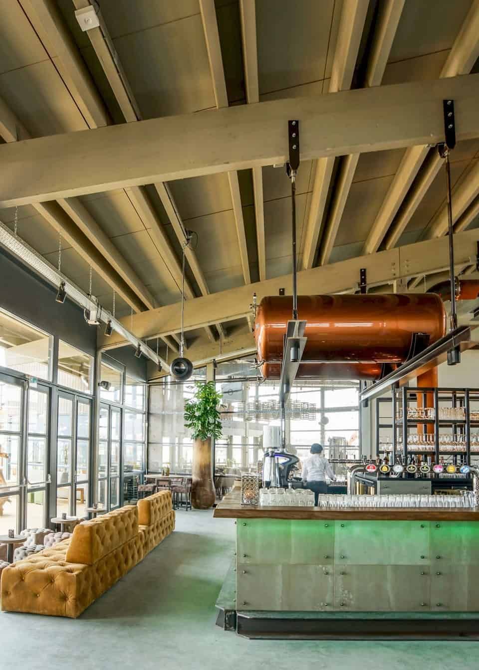 Industrieel restaurant met betonnen en houten bar en okergele bank