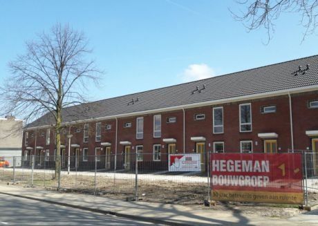 Rode stenen huizen met zwart dak met banner van Hegeman Bouwgroep
