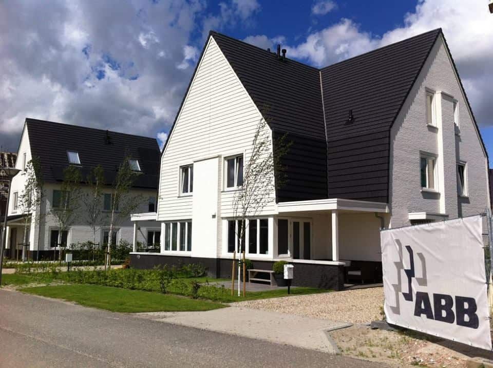 Net nieuw wit huis met zwart dak en grasveld als voortuin