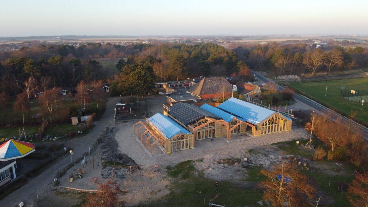 Houten gebouw met grijze en blauwe daken middenin de natuur