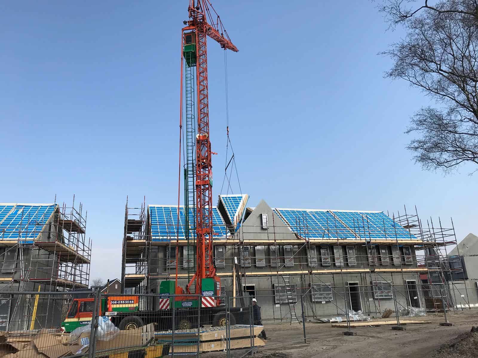 Hoge rode kraan naast huis in aanbouw