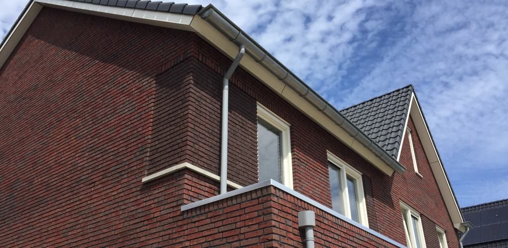 Rood nieuwbouwhuis met zwart dak en op de achtergrond sluierbewolking