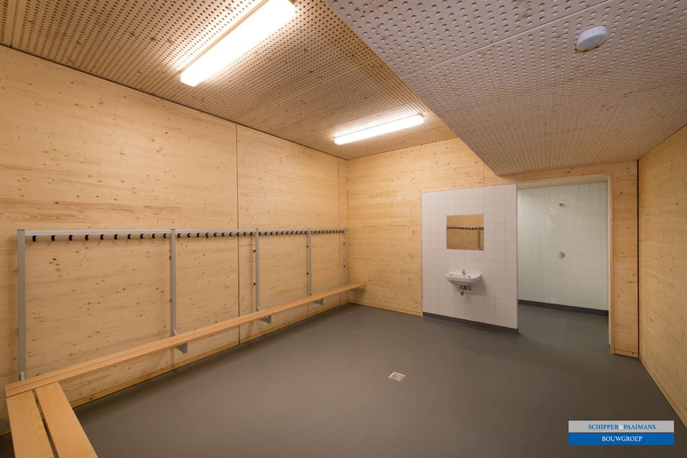 Houten kleedkamer met bankjes en kapstokken