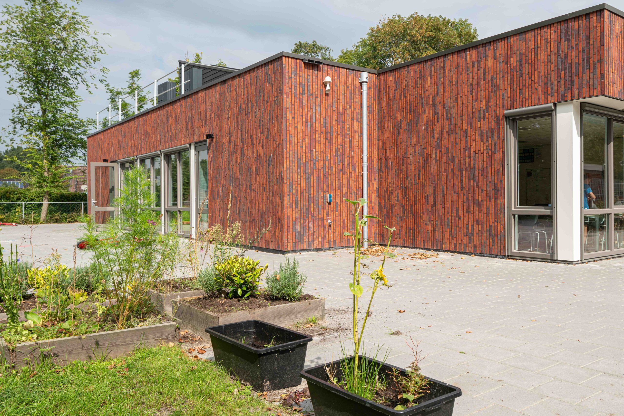 De zijkant van school In 't Zandt met een moestuintje