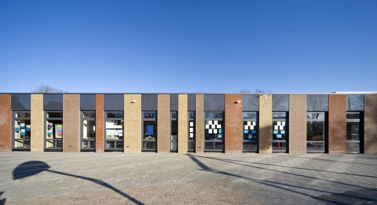 Gebouw van verschillende kleuren bakstenen met lange ramen en papieren op de ramen