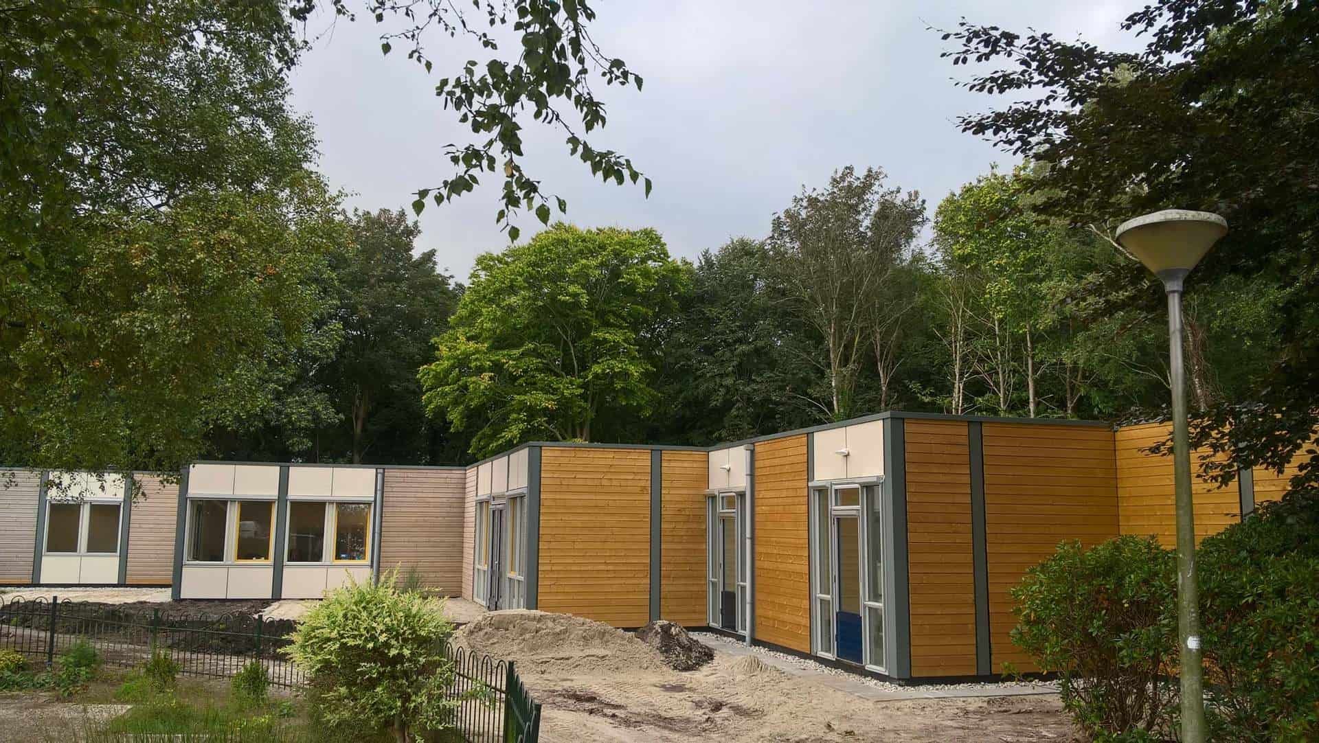 Houten woningen langs pad met bomen
