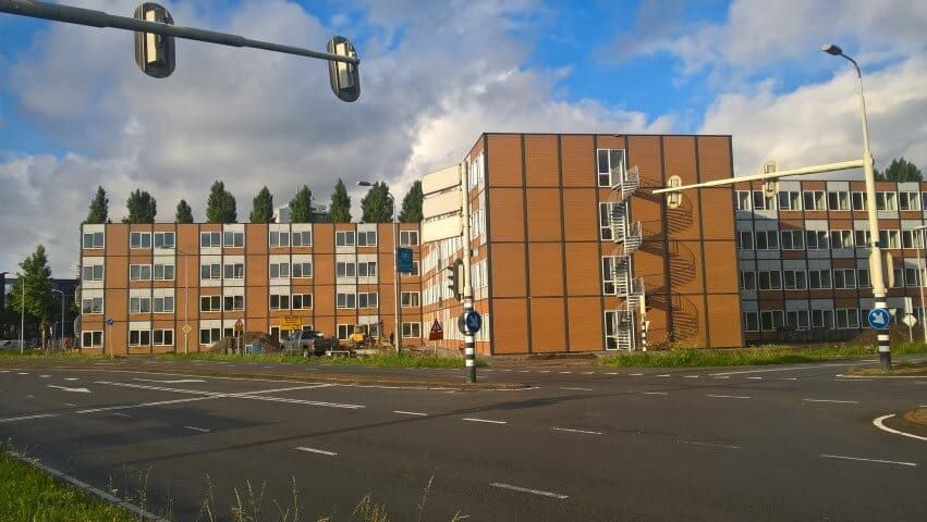 Houten flatgebouw aan een weg met stoplichten