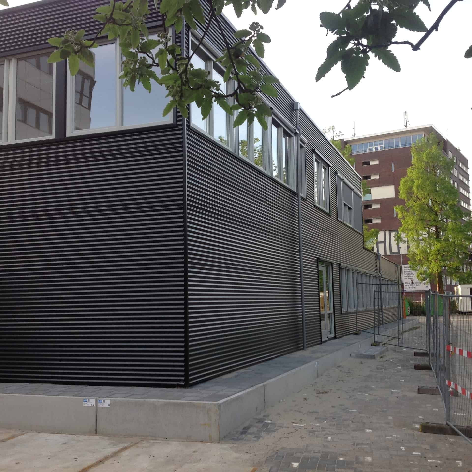De hoek van het zwarte gebouw van het UMCG met bomen