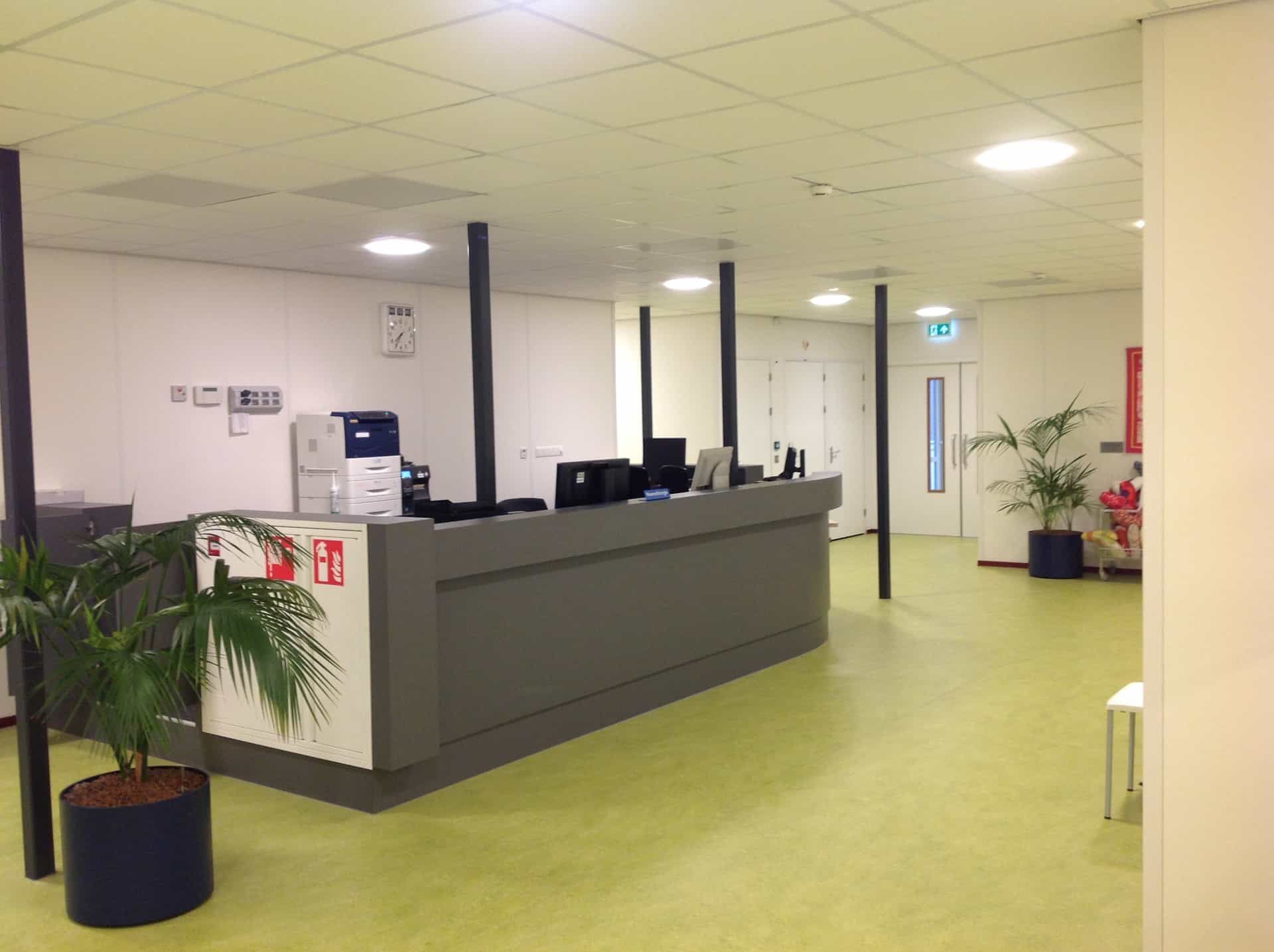 De zwart met witte balie op een groene vloer van de poli UMCG