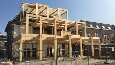 Aanbouw met houten constructie aan een huis met hekken ervoor