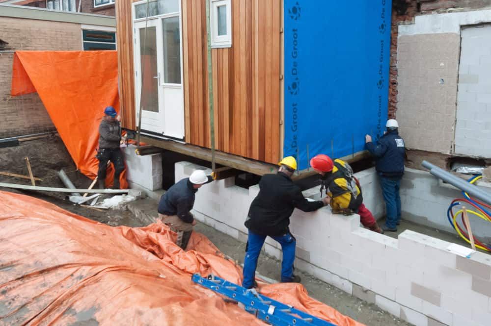 Bouwvakkers die een bruine box met witte deuren plaatsen