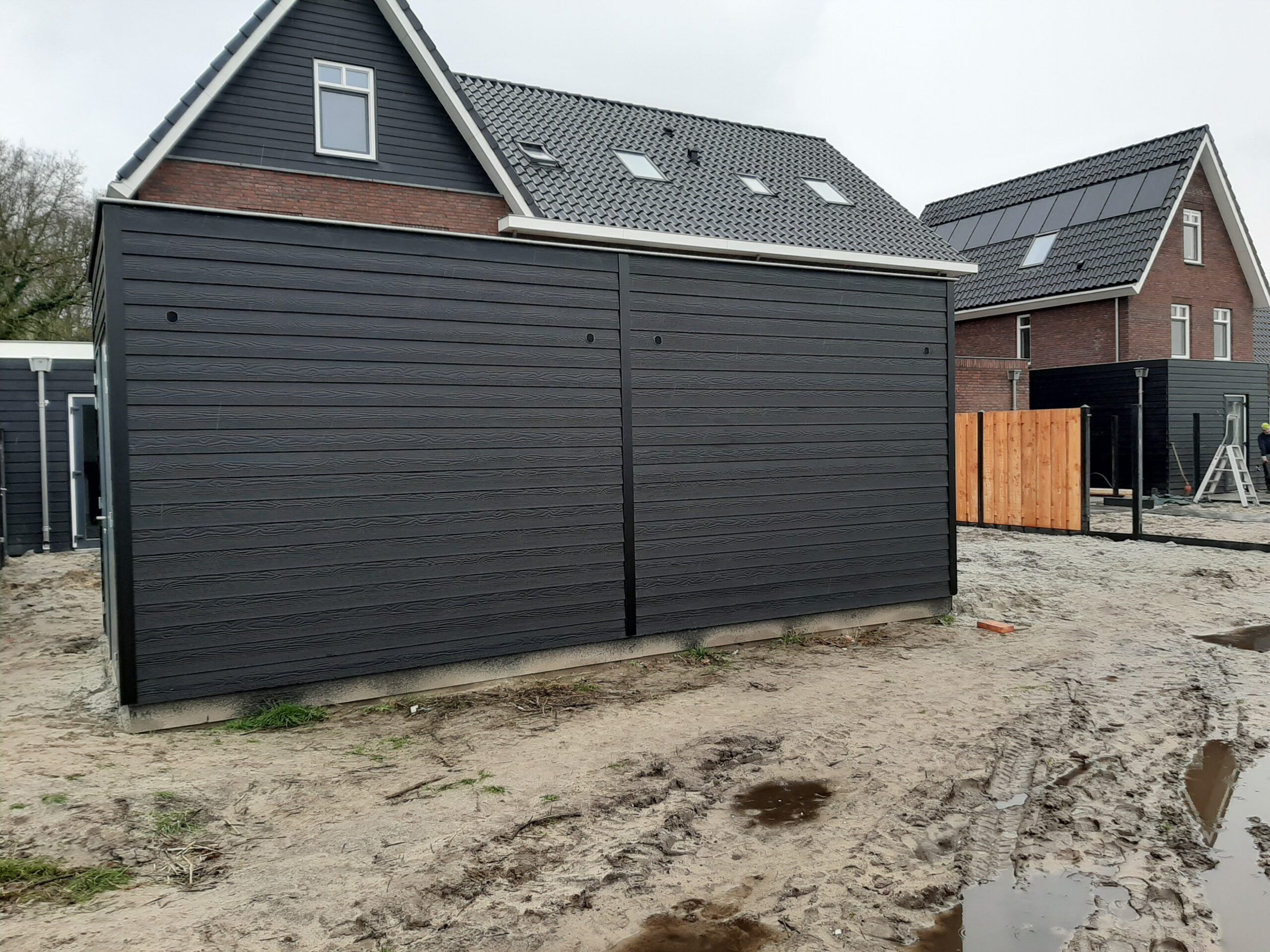 Houten berging zwart bij een nieuwbouwhuis