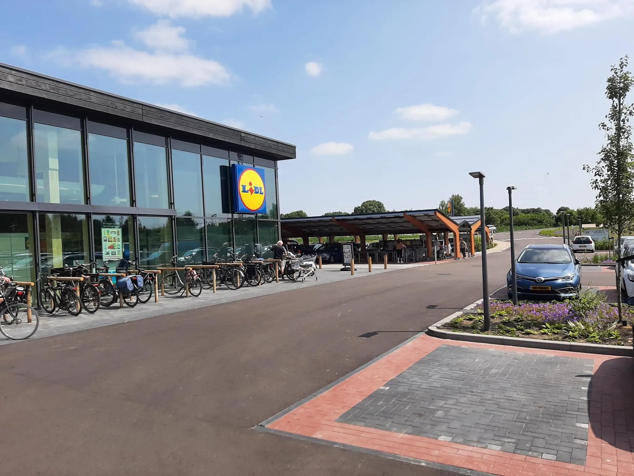 Glazen gebouw van de Lidl met parkeerplaats ervoor