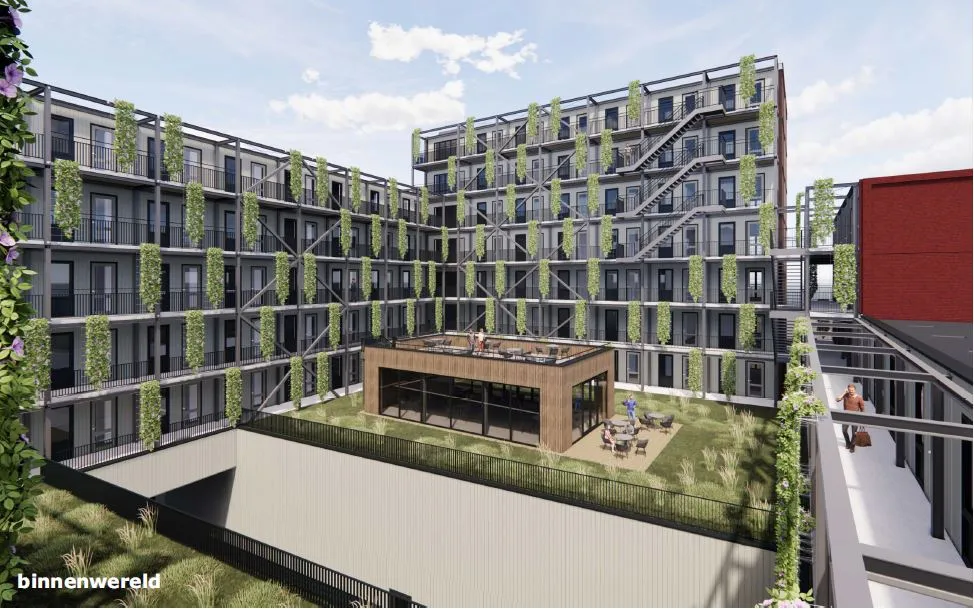 Een binnenplaats met veel groen en in het midden een houten vierkant gebouw