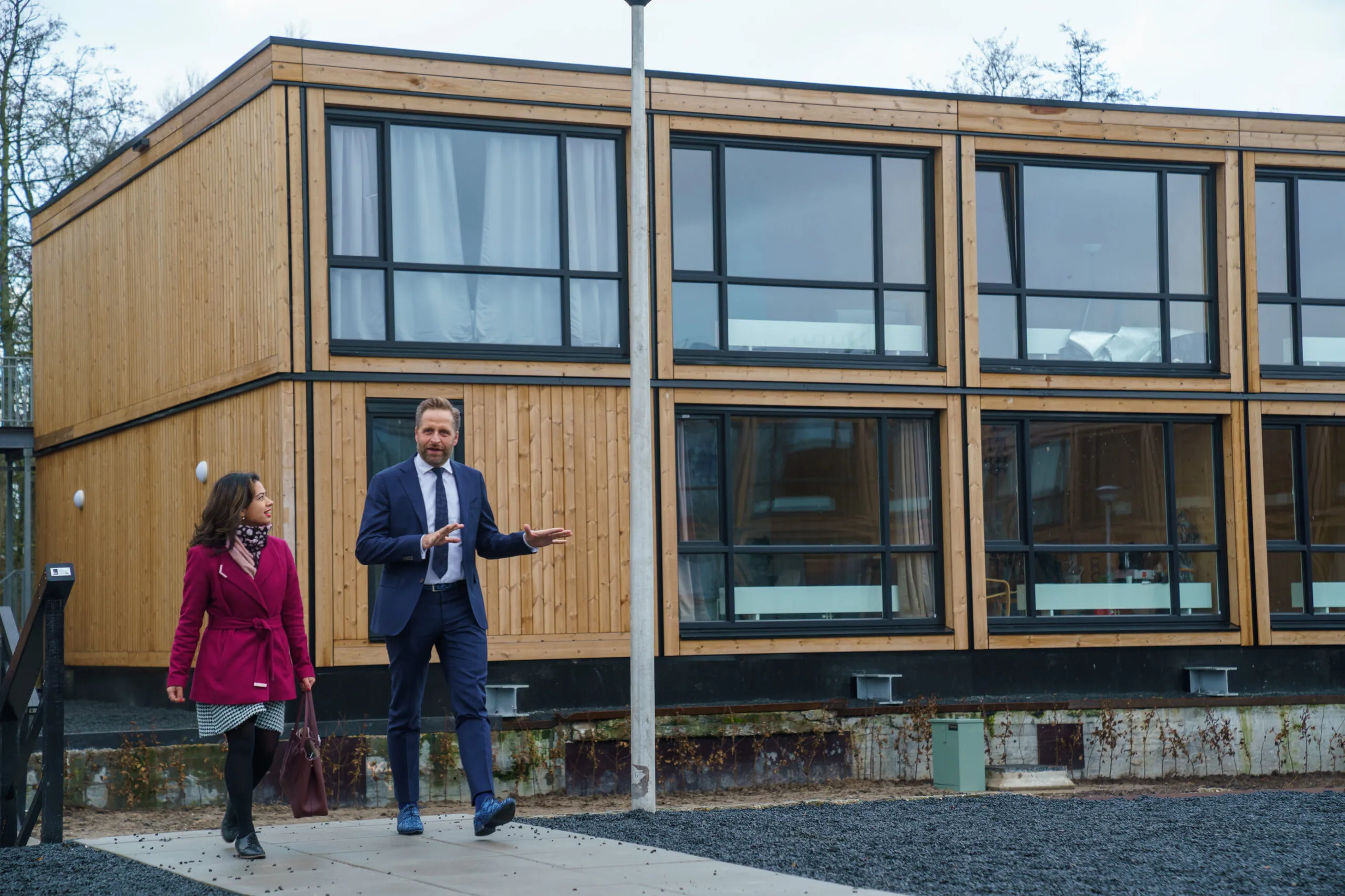 Hugo de Jonge in gesprek met met een vrouw buiten lopend voor een houten gebouw