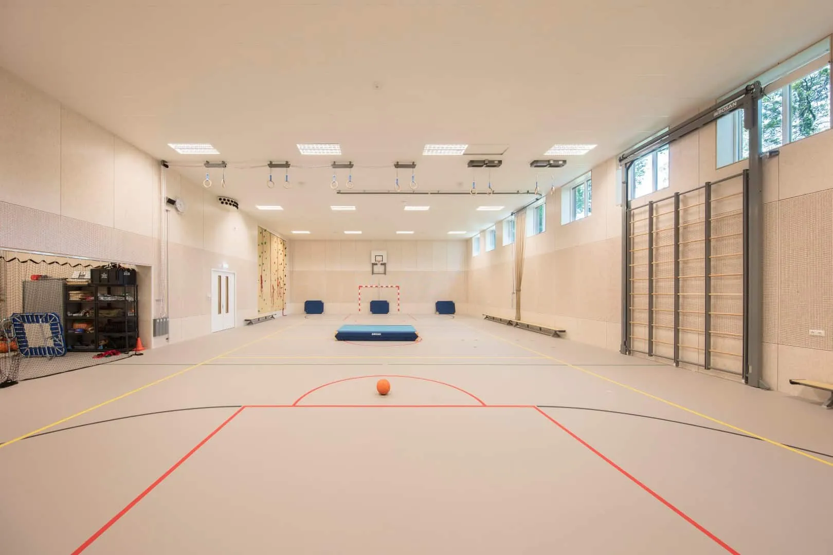 De sportzaal van het Wellantcollege met lichte kleuren, strepen op de grond, sportattributen en een opberghok links