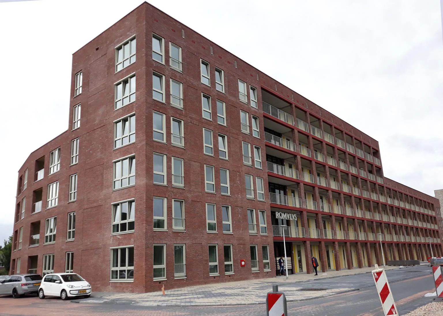 Bakstenen gebouw met veel ramen aan een straatkant