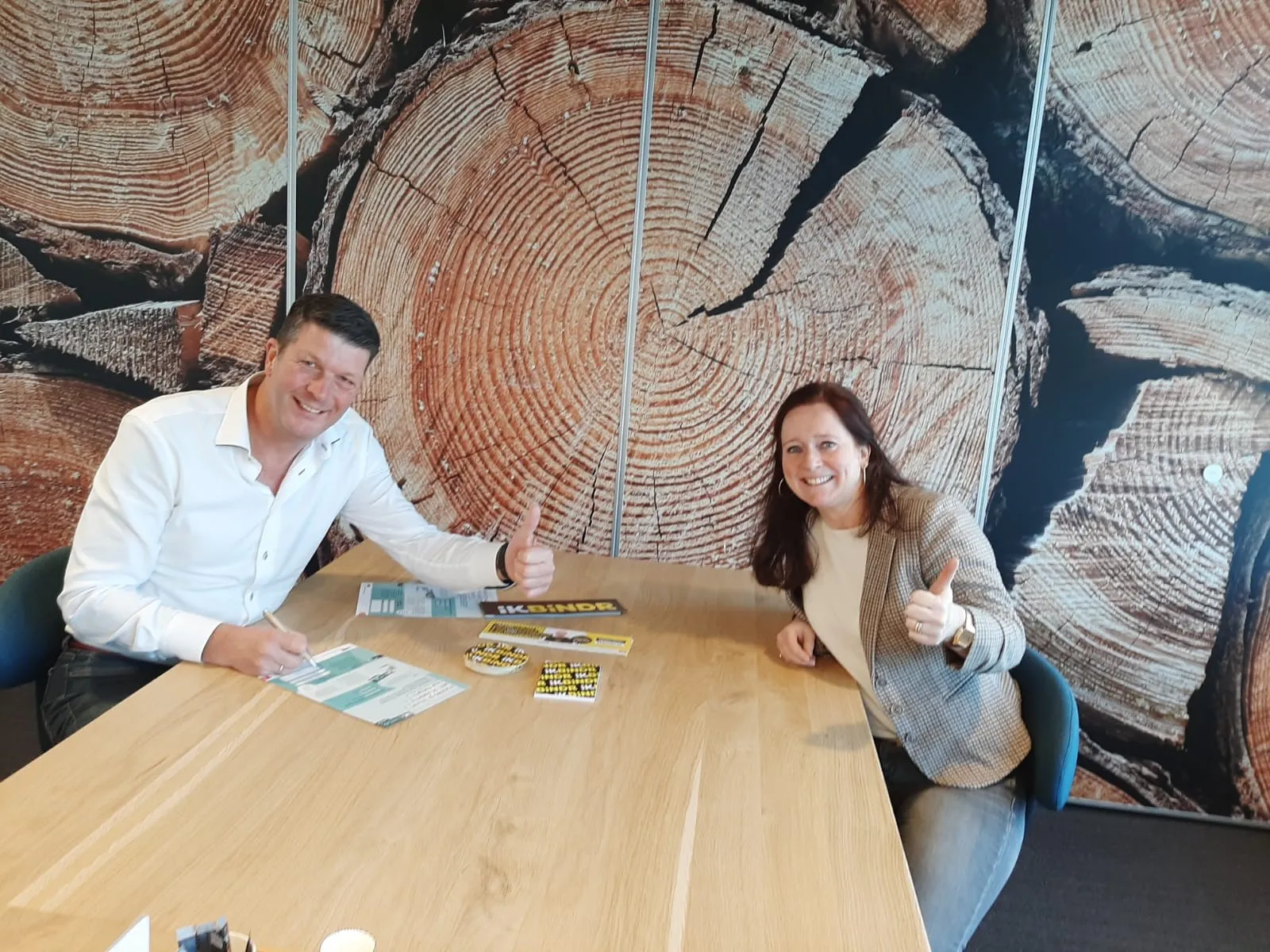 Twee personen tekenen contract aan een houten tafel met behang van hout