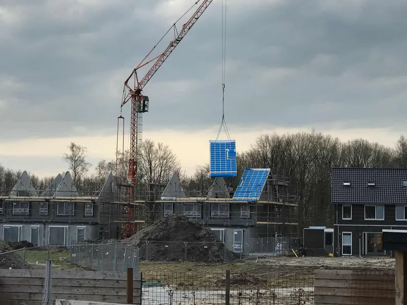 Blauw dak die wordt vervoerd door een rode hoge kraan