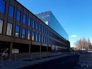 Gebouw met veel ramen en glas en onderaan parkeerplekken