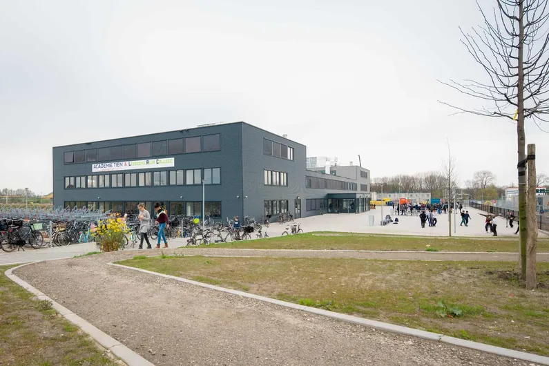 Grijs gebouw met een weg en grasveld van de Nuovo scholengroep