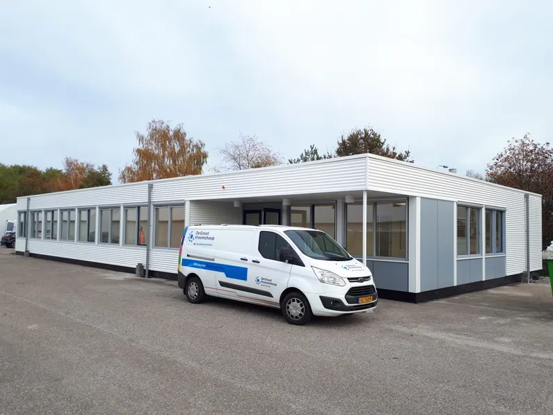 Het wit met grijze gebouw van de bedrijfsvakschool van Volkerswessels met het busje van De Groot Vroomshoop
