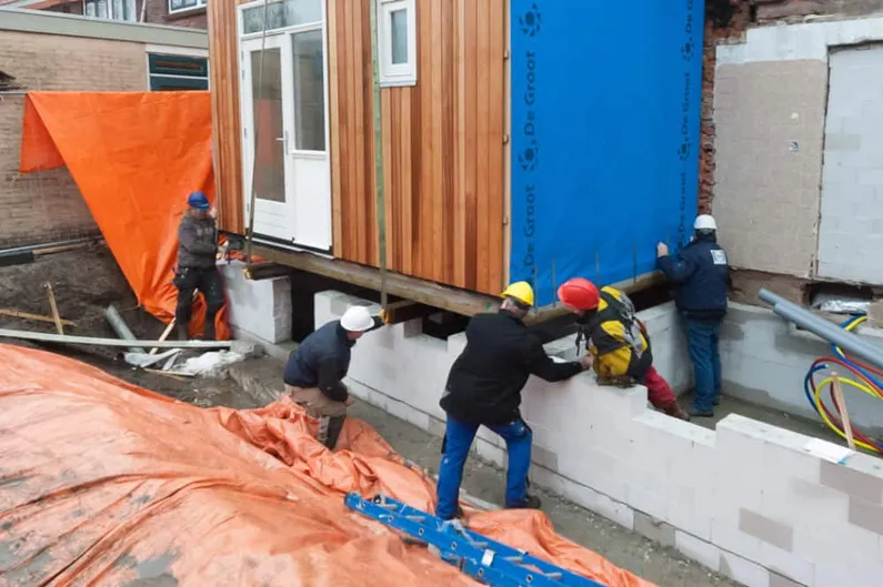Bouwvakkers die een bruine box met witte deuren plaatsen