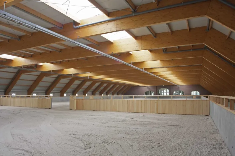 Rijhal met wit zand en lichtbruine houten afscheiding